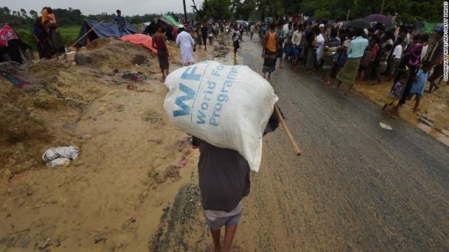 TOPSHOT - A Rohingya Muslim refugee carries a rice bag along a road near Balukhali refugee camp near the Bangladesh town of Gumdhum on September 17, 2017. - Heavy monsoon rain heaped new misery September 17 on hundreds of thousands of Muslim Rohinyga stuck in makeshift camps in Bangladesh after fleeing violence in Myanmar, as authorities started a drive to force them to a new site. The United Nations says 409,000 Rohingyas have now overwhelmed Cox's Bazar since August 25 when the military in Buddhist-majority Myanmar launched operations in Rakhine state. (Photo by DOMINIQUE FAGET / AFP) (Photo by DOMINIQUE FAGET/AFP via Getty Images)