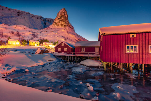 Popular tourist destination - Gravdalbukta bay. Attractive sunset on Lofoten Islands archipelago. Exciting evening cityscape of Reine town, Norway, Europe.  Life over polar circle.