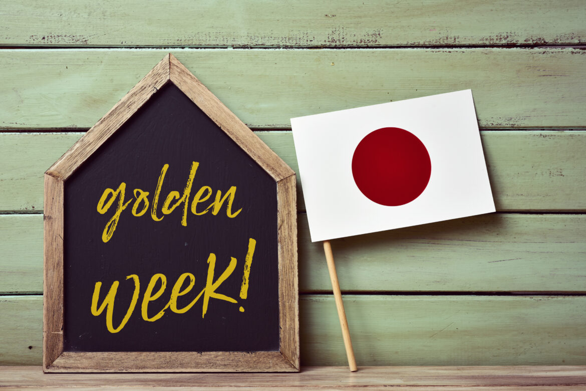 a house-shaped blackboard with the text golden week written in it and a flag of japan, against a pale green rustic wooden background