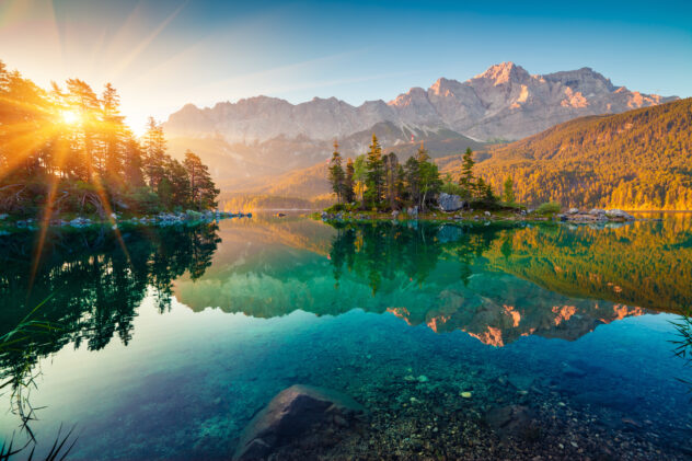 Impressive summer sunrise on Eibsee lake with Zugspitze mountain range. Sunny outdoor scene in German Alps, Bavaria, Germany, Europe. Beauty of nature concept background.