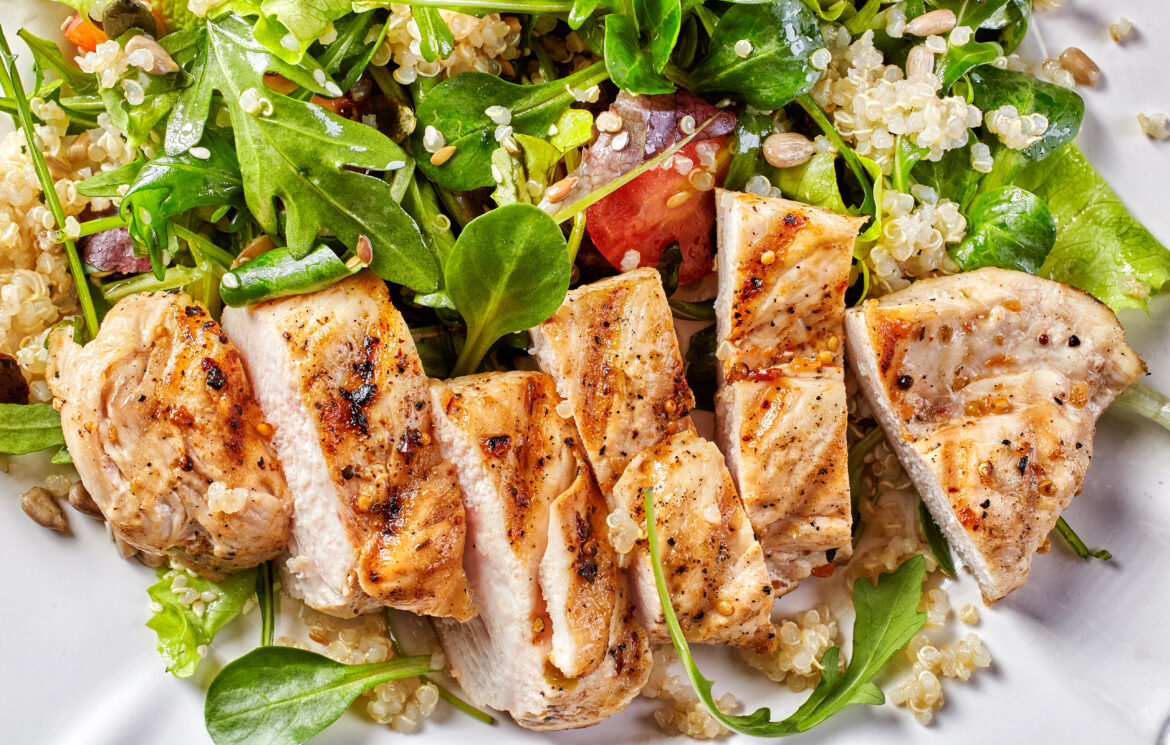 Quinoa and vegetable salad with grilled chicken fillet, top view