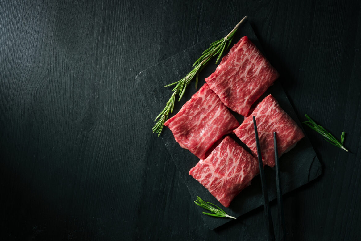 Sliced wagyu marbled beef for yakiniku on plate on black background, Premium Japanese meat, top view and copy space