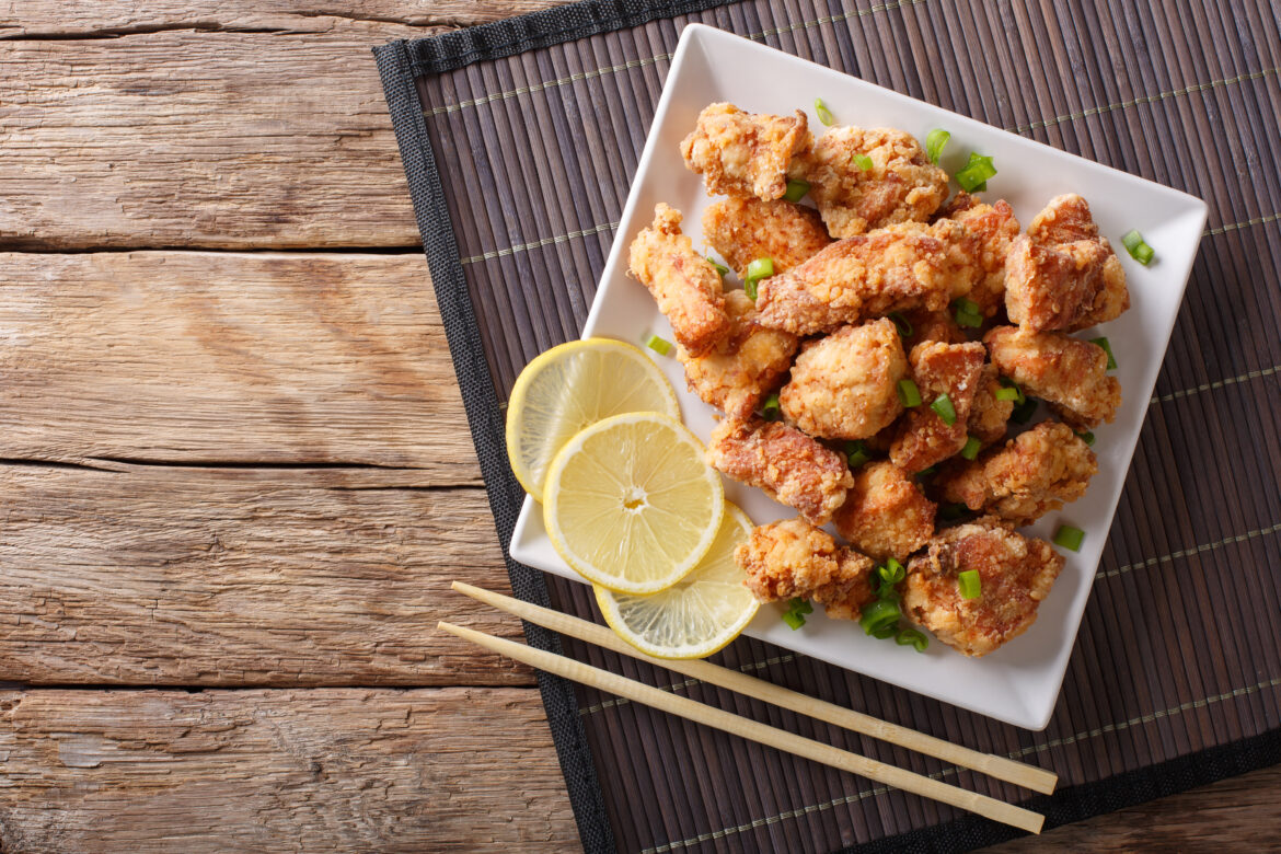 Spicy chicken karaage with lemon and green onion close-up. horiz