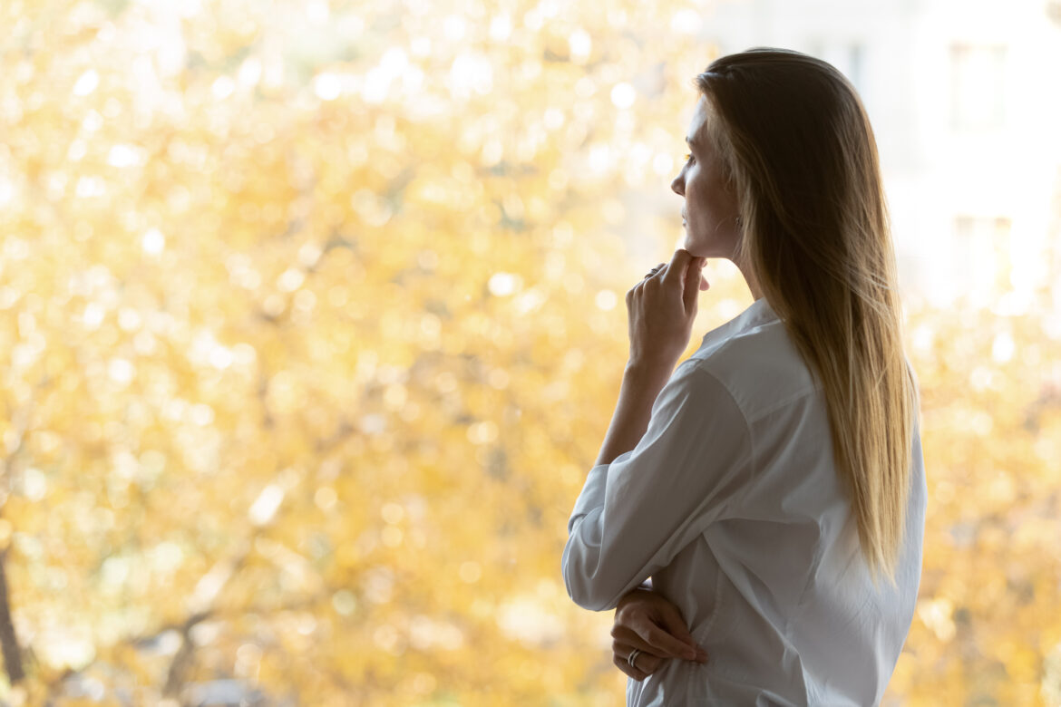 Side view pensive businesswoman touches chin as symbol of thinking and consideration, female ceo standing in office room looking out window search solutions feels concerned, concept of business vision