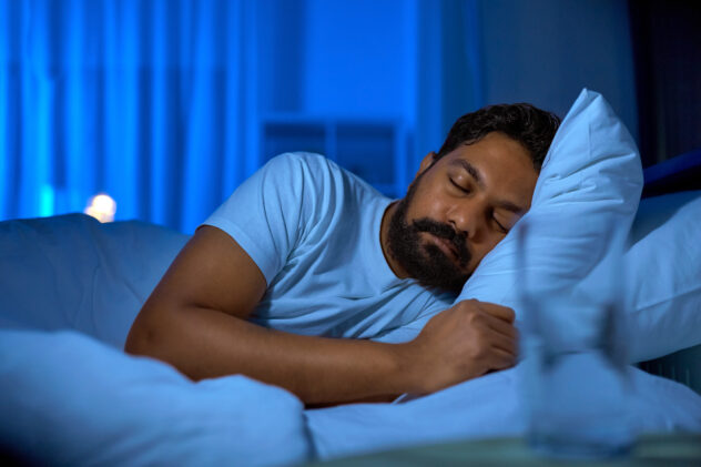 people, bedtime and rest concept - indian man sleeping in bed at home at night